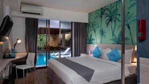 Ein Hotelzimmer mit Bett, Schreibtisch, Stuhl, Fernseher, einem roten Feuerlöscher und Blick auf Poolanlage und Außenbereich.