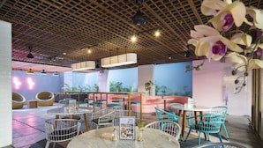 Ein Restaurant mit runden Tischen und Stühlen, einer Holzbalkendecke und Blumentöpfen.