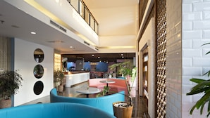 Eine moderne Hotelhalle mit einer gebogenen, blauen Couch, einem Empfangstisch und einem Essbereich.