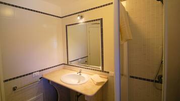 Une salle de bain avec un lavabo, un miroir et une douche.