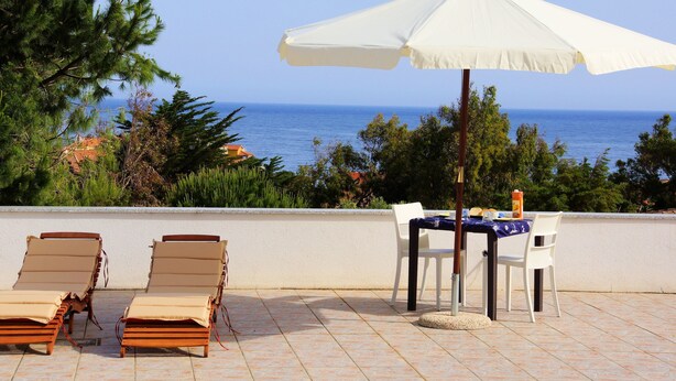 A terrace with two sun loungers, a table with chairs, and a white umbrella. - Hotel Tartaruga Bianca (Valledoria)