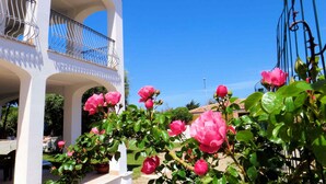 A white building with a balcony and a garden with pink flowers. - Hotel Tartaruga Bianca (Valledoria)