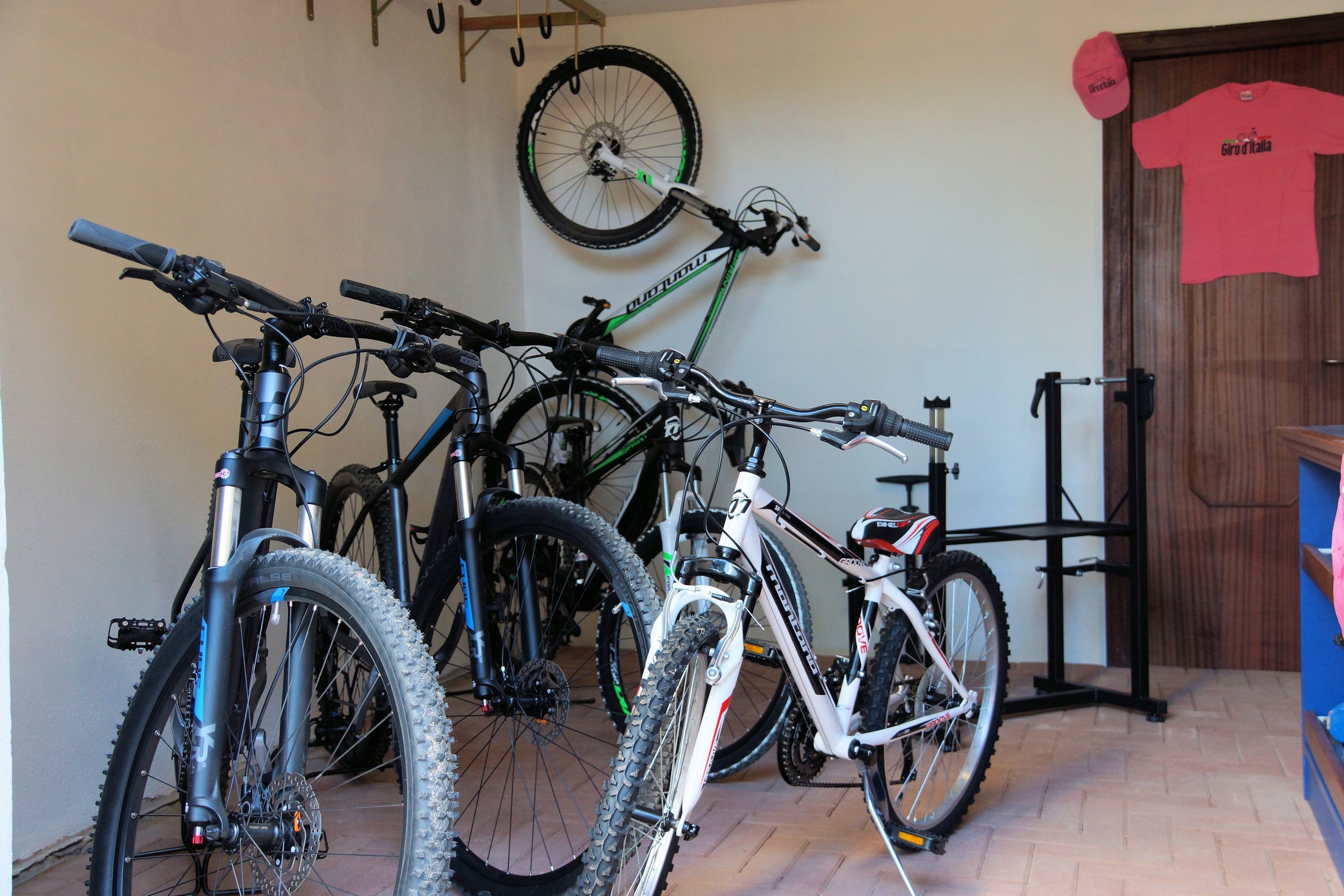 Una habitación con bicicletas, una puerta y un neumático colgado en la pared.