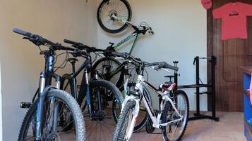 Una habitación con bicicletas, una puerta y un neumático colgado en la pared.
