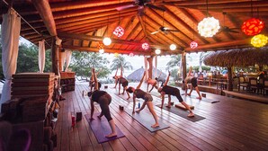 A wooden deck with yoga mats and blocks, a ceiling fan, and hanging decorative lights. - Present Moment Retreat (Troncones)