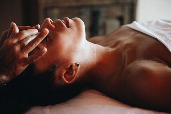 A person lying down with their head turned to the side, resting on a pillow. - Present Moment Retreat (Troncones)