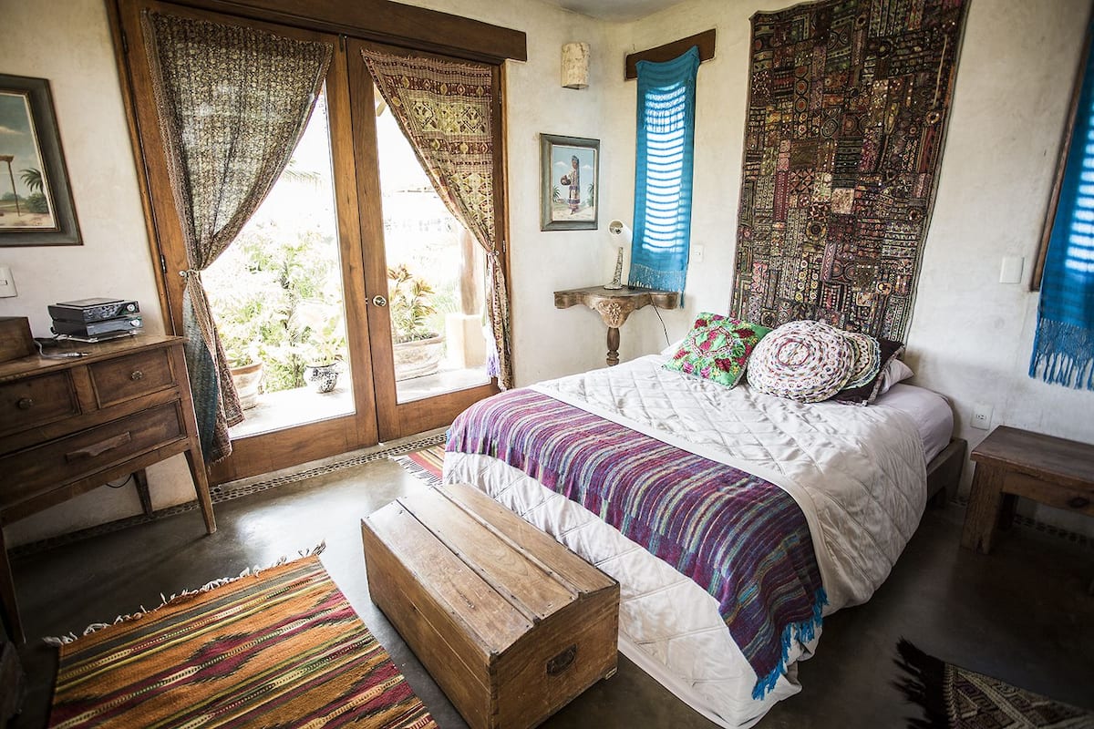 Un dormitorio con una cama grande, un cofre de madera y vistas al exterior a través de una puerta corredera.