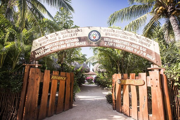 A wooden gate with a sign indicating the entrance to a facility offering yoga, massage, and various dining options.