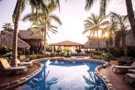 Una piscina al aire libre, sombrillas, sillones reclinables de piscina. Present Moment Retreat