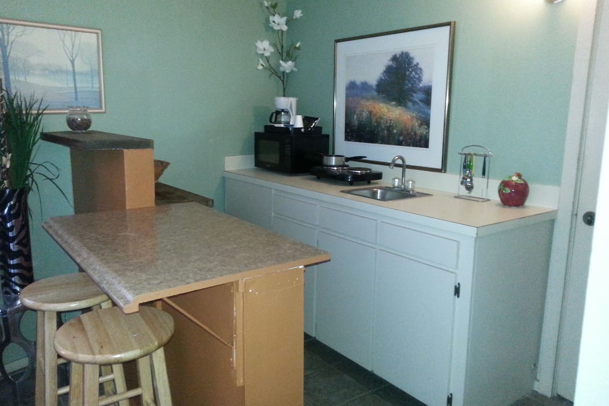A compact kitchen with a sink, microwave, and a small island with stools.