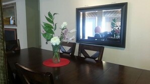 Ein Essbereich mit einem dunklen Holztisch, einer Blumenvase und einem großen, gerahmten Spiegel an der Wand.