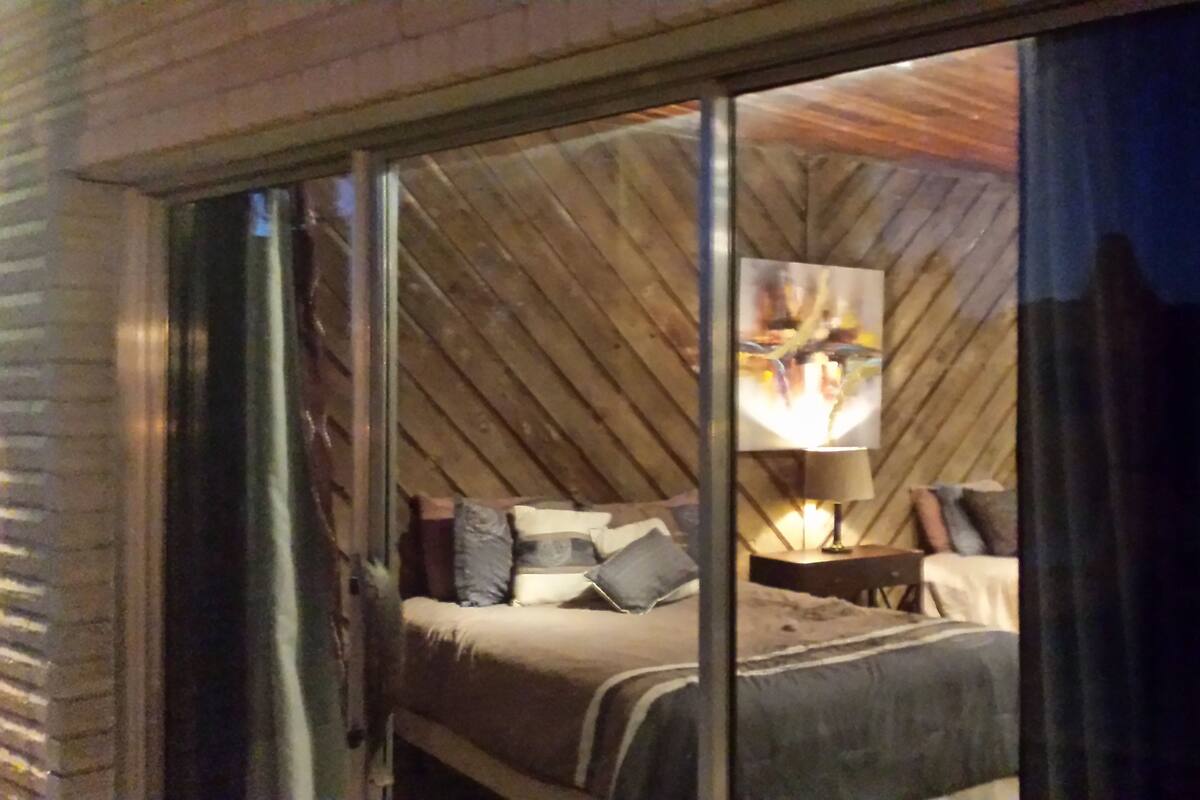 A bedroom with a bed, pillows, a nightstand, and a lamp.