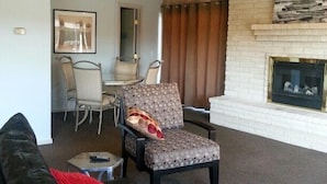 Ein Wohnzimmer mit schwarzem Ledersofa, einem gemusterten Sessel und einem Kamin.