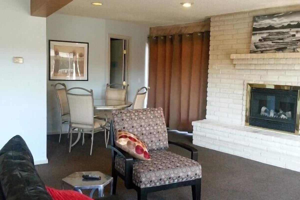 A living room with a black leather sofa, patterned armchair, and a fireplace.
