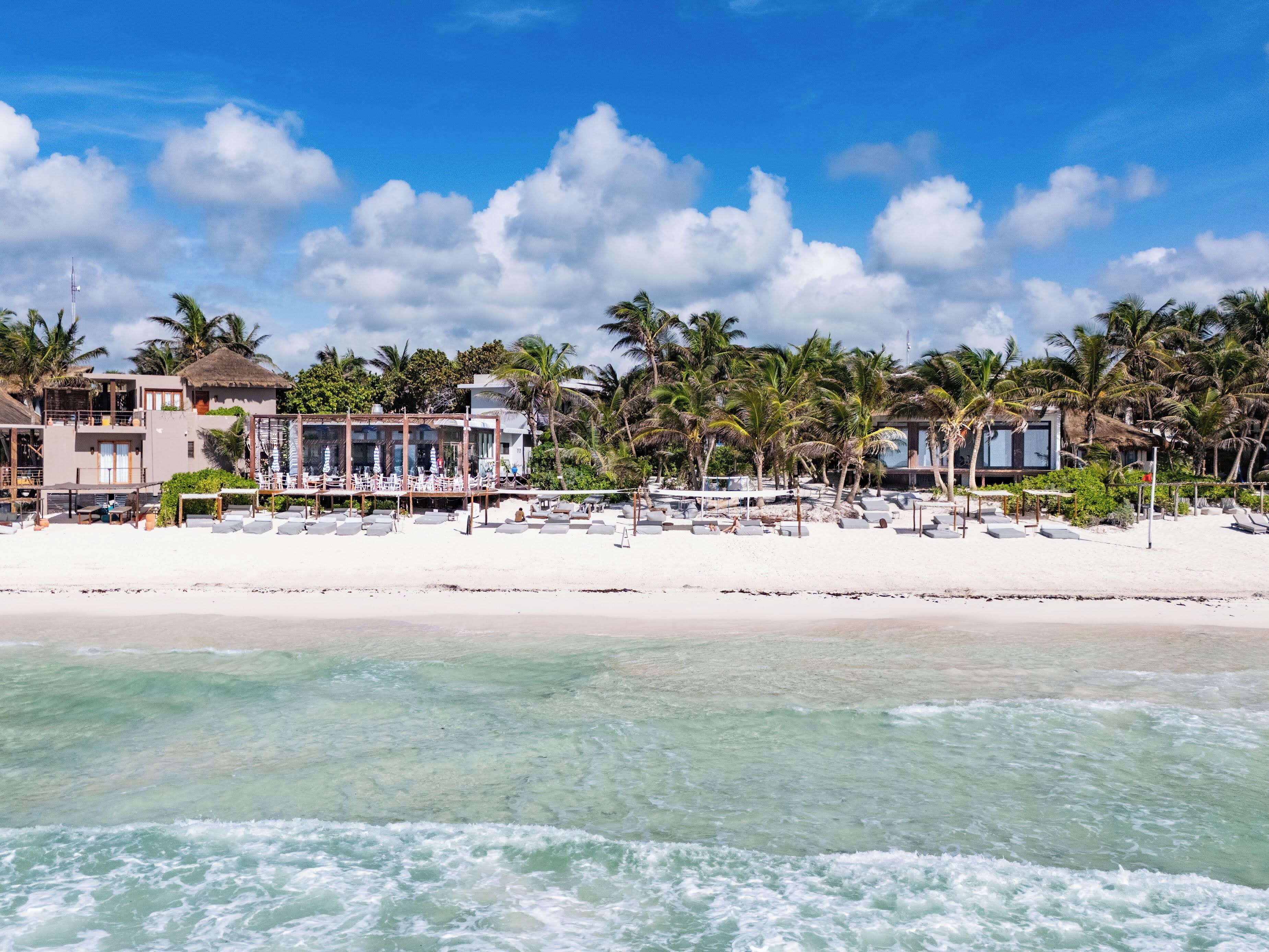En la playa, playa de arena blanca, camastros y sombrillas 