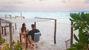 A beachside dining area with wooden tables and chairs, overlooking the ocean. - Lula Tulum, a Small Luxury Hotel (Tulum)