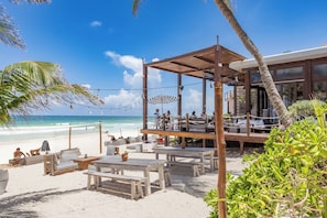 Na praia, areia branca, espreguiçadeiras, guarda-sóis 