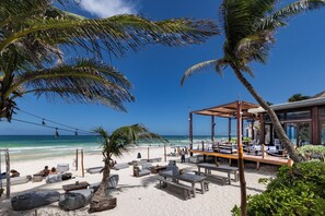 A beachside lounge with outdoor seating, a pool, and a view of the ocean. - Lula Tulum, a Small Luxury Hotel (Tulum)