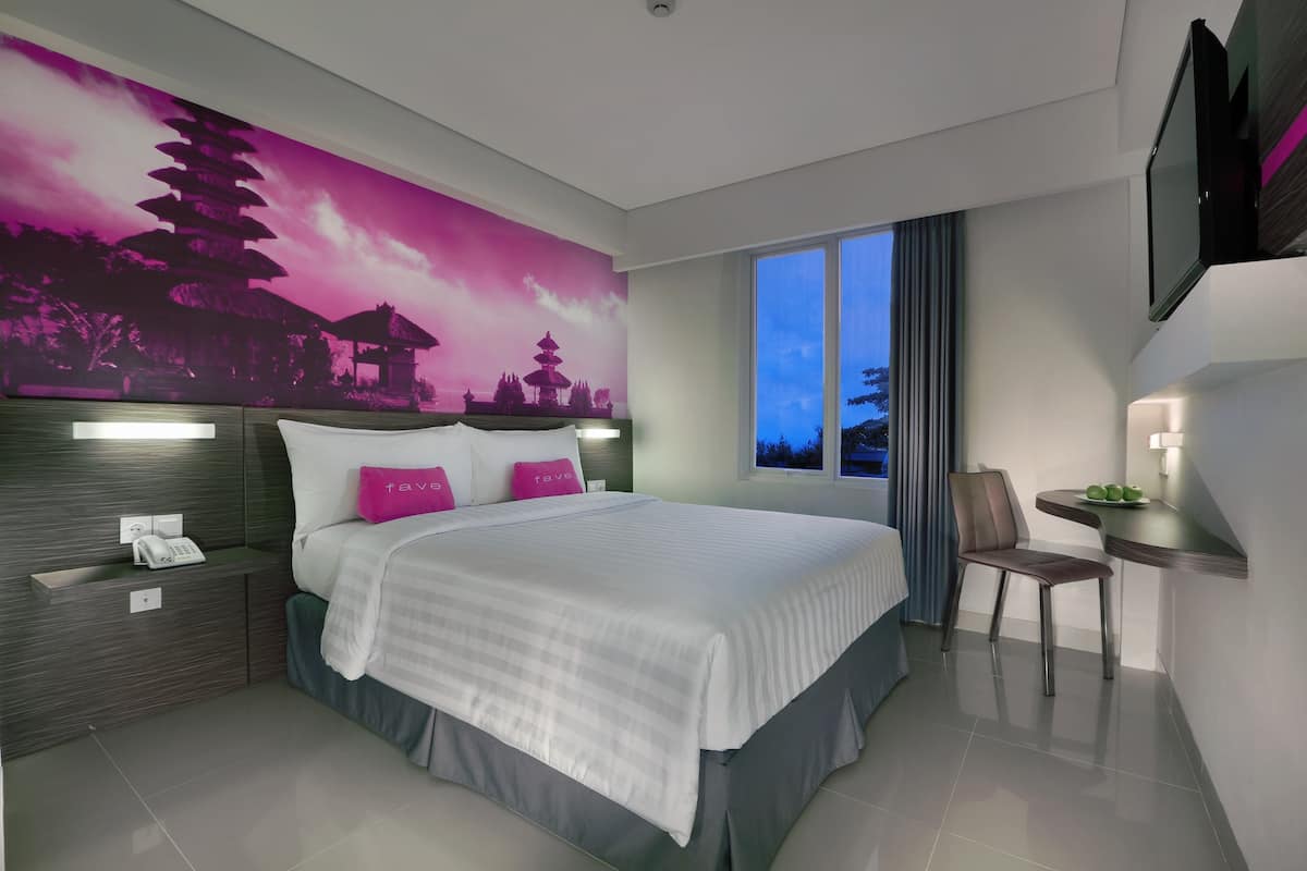 A modern hotel room with a large bed, a desk, and a chair.
