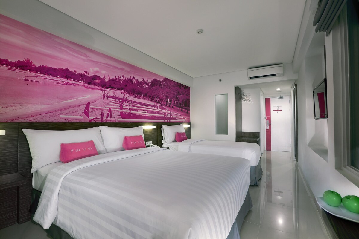 A hotel room with two beds, a large pink mural on the wall, and a hallway leading to another room.