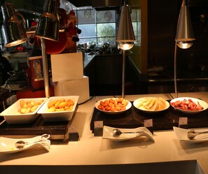 A buffet with various dishes and utensils, including plates of food and serving spoons. - Aloft Guangzhou University Park (Guangzhou)