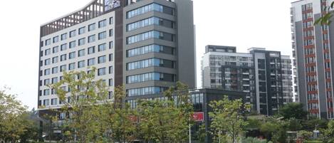 A modern hotel with multiple floors, large windows, and a rooftop terrace.