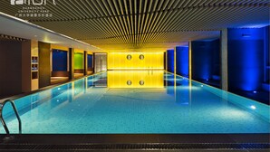 A modern indoor swimming pool with a wooden ceiling and bright yellow lighting. - Aloft Guangzhou University Park (Guangzhou)