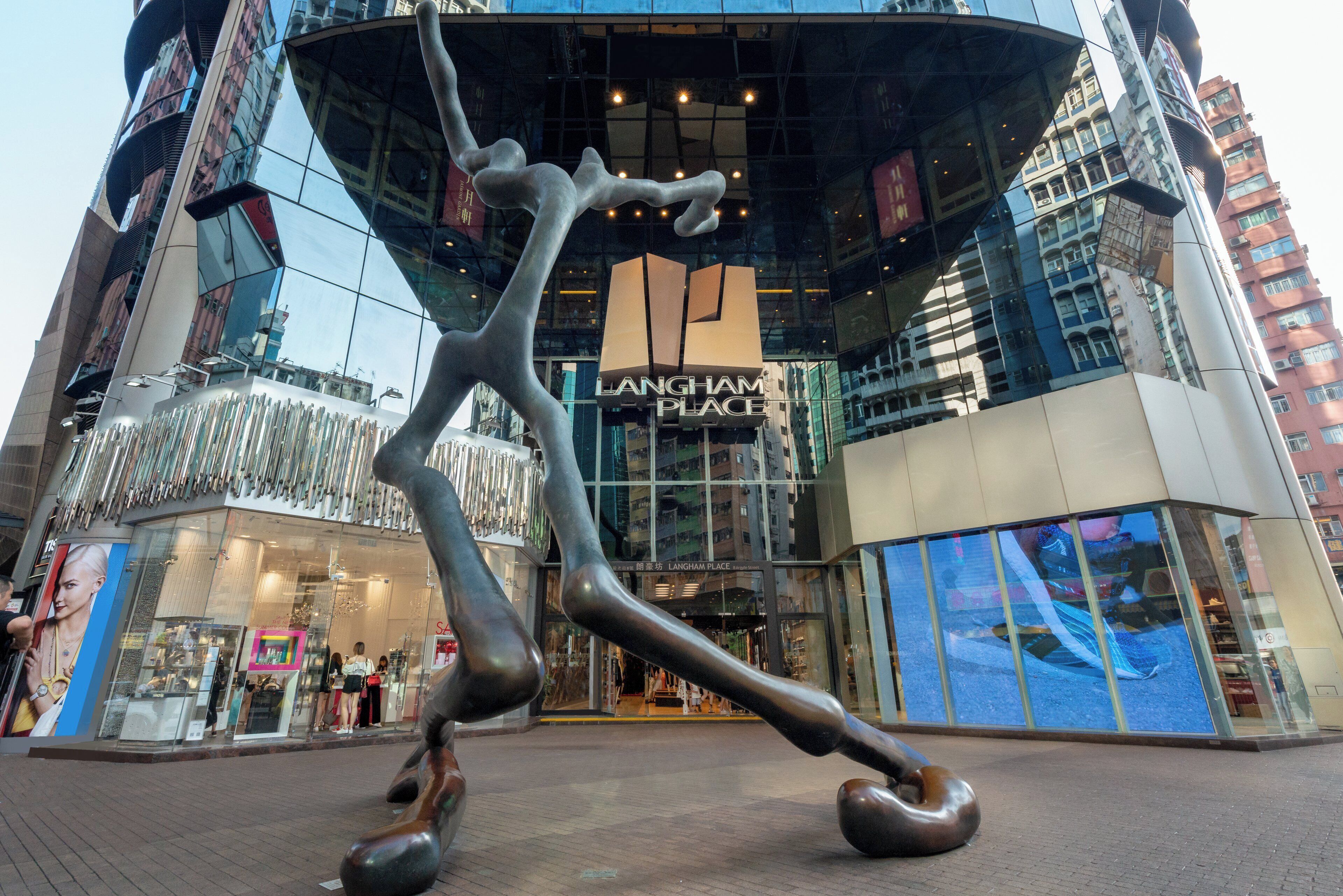 Una escultura moderna frente a un edificio con un cartel que dice 'LANGHAM PLACE'.