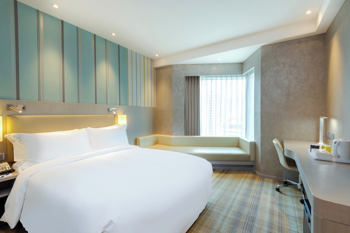 Habitación de hotel con una cama grande, un escritorio y una zona de estar.