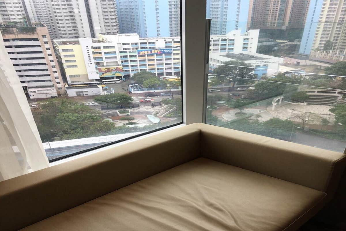 A room with a large window overlooking a cityscape, featuring high-rise buildings and a road with vehicles.
