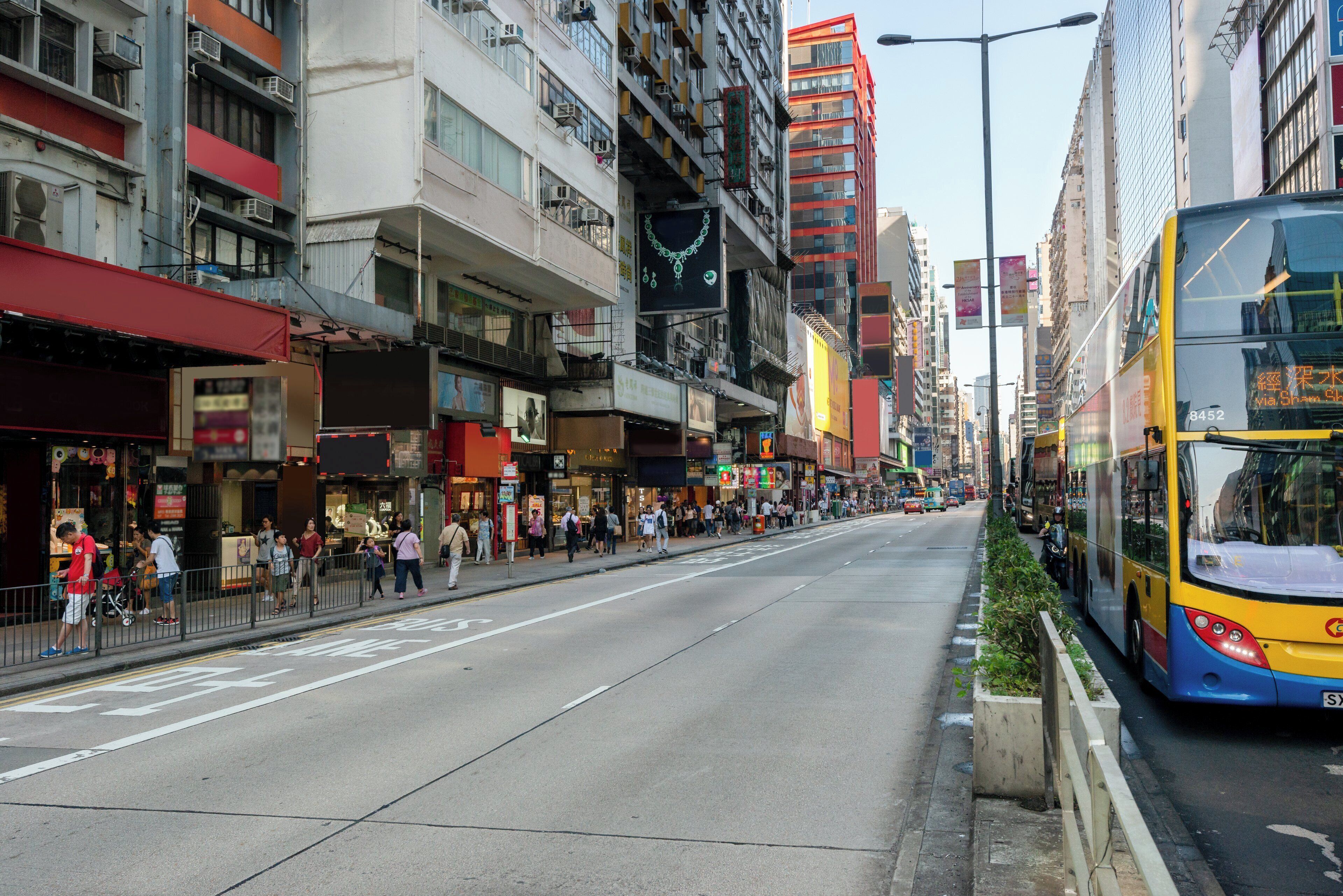 A street with buildings, a bus, and pedestrians.