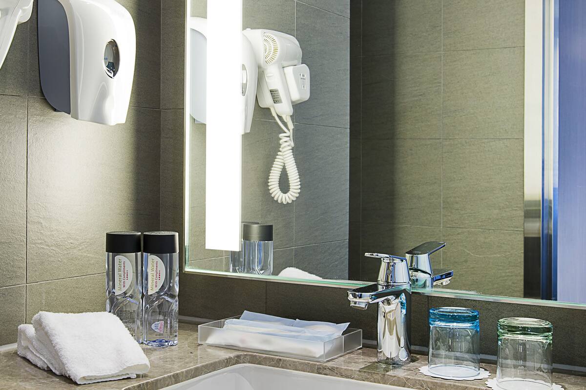 A modern bathroom with a sink, mirror, towel, and toiletries.
