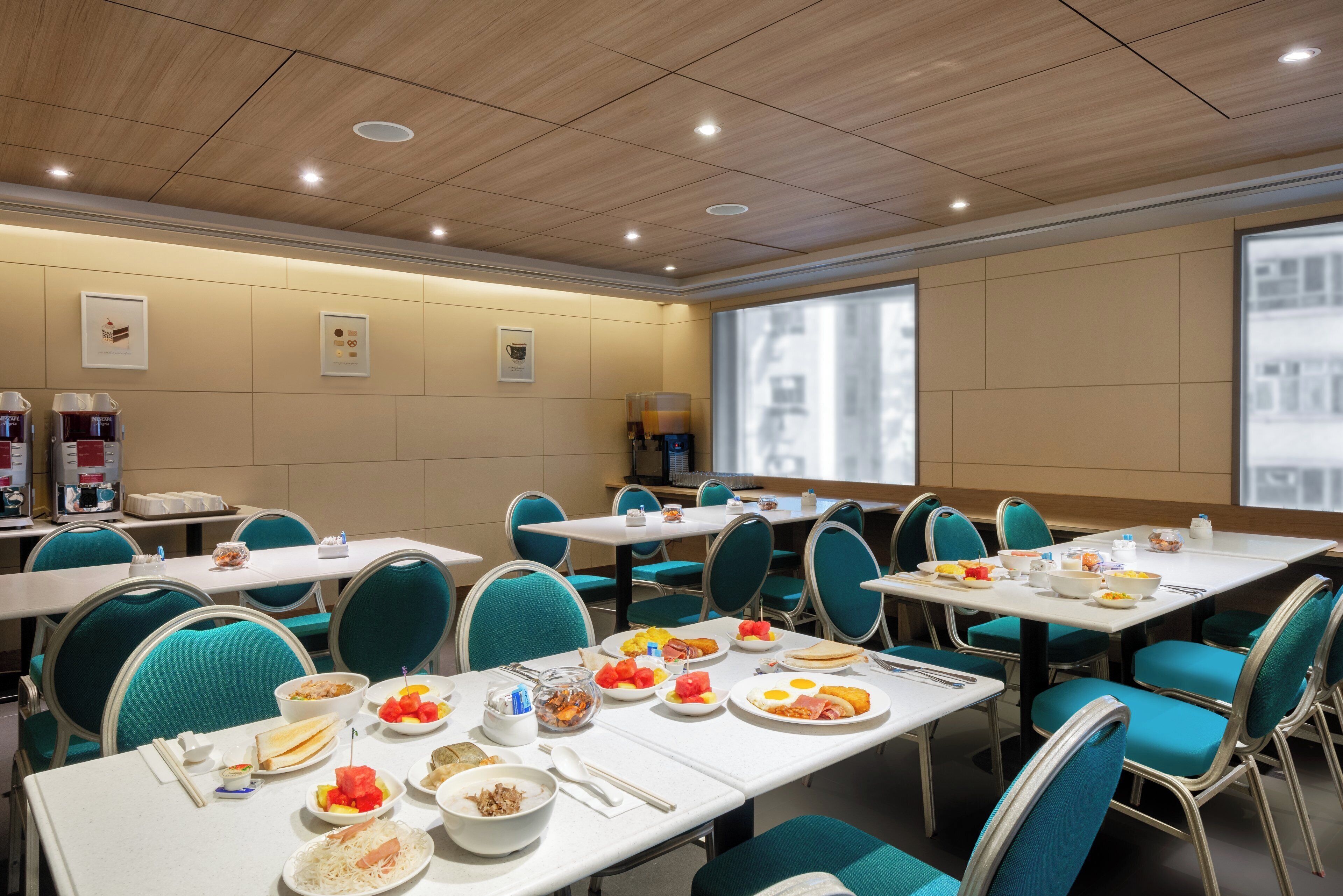 A dining area with multiple tables and chairs, equipped with coffee machines and a variety of breakfast items.