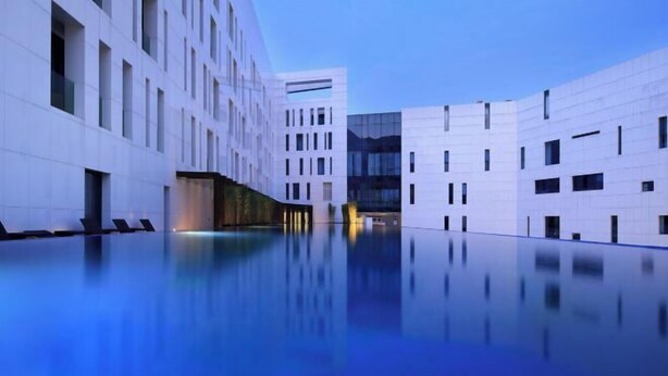 Un edificio moderno con una piscina a specchio antistante.