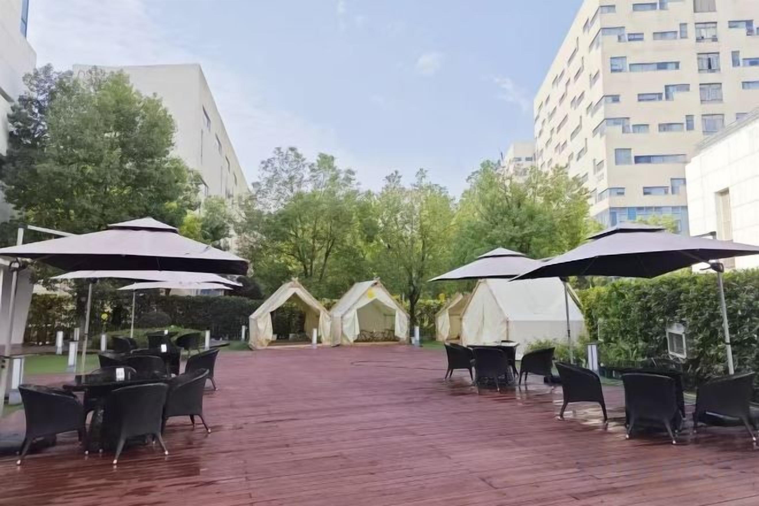 An outdoor patio with tables and chairs, umbrellas, and tents.