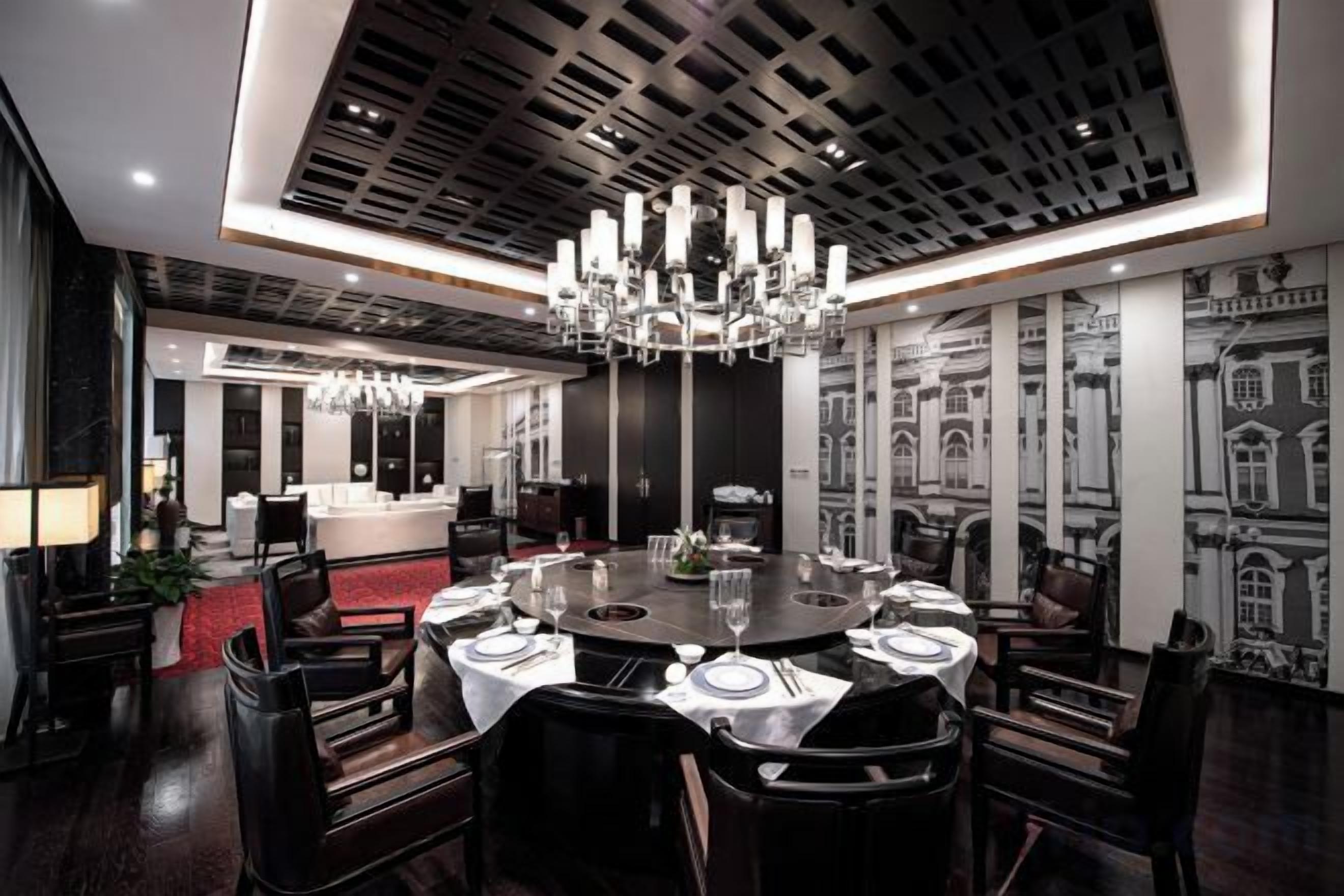 A modern dining area with a round table set for six, surrounded by dark wooden chairs.