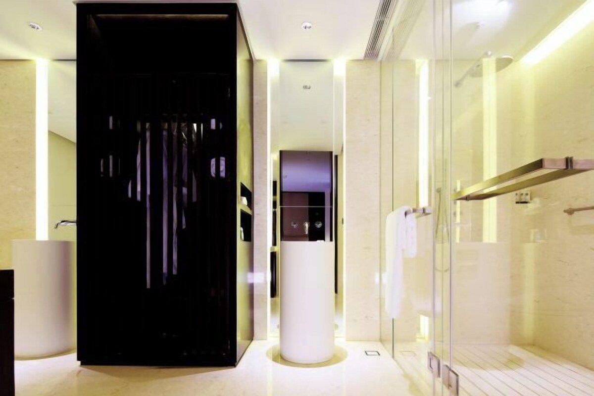 A modern bathroom with a glass shower, a black cabinet, and a white sink.