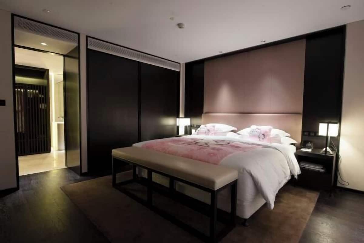 A modern bedroom with a large bed, bedside tables, and a bench.
