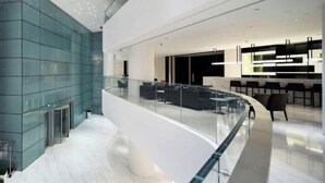 Un interno moderno con ringhiera in vetro, una zona salotto e una cucina con pensili neri.
