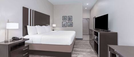 A modern hotel room with a large bed, bedside tables, a TV, and a shower area.
