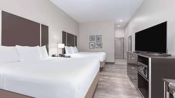 A hotel room with two beds, a TV, a microwave, and a small kitchenette.