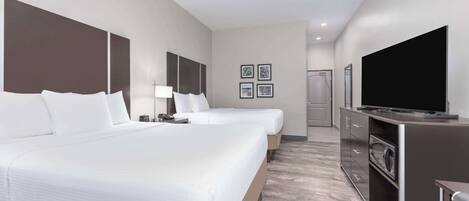 A hotel room with two beds, a TV, a microwave, and a small kitchenette.