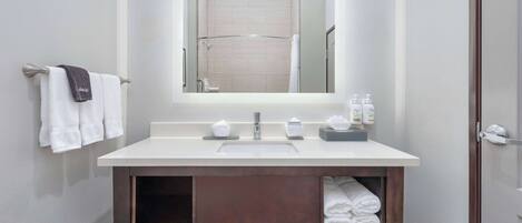 A modern bathroom with a white sink, a large mirror, and a towel rack.