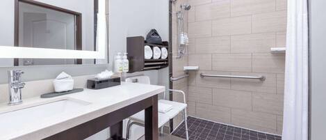 Un bagno moderno con un lavandino bianco, uno specchio, una doccia con porta in vetro e un porta asciugamani.
