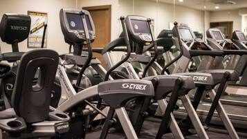 A row of stationary bikes with digital displays, branded with 'CYBEX', in a gym setting.