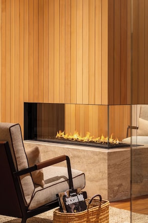 A modern living room with a fireplace, a comfortable chair, and a basket with books. - Hotel Jackson (Jackson)