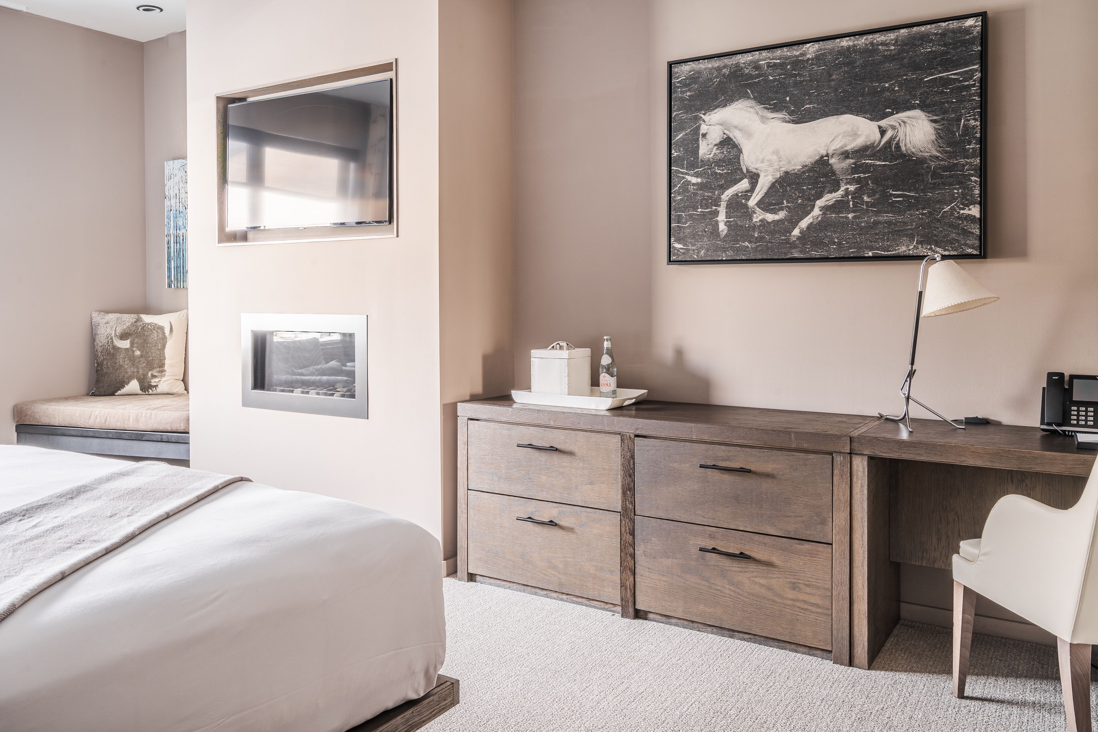 A bedroom with a bed, a desk, a chair, and a mounted artwork of a horse.