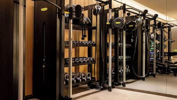 Un gimnasio con equipo de levantamiento de pesas, una banca y un espejo grande.