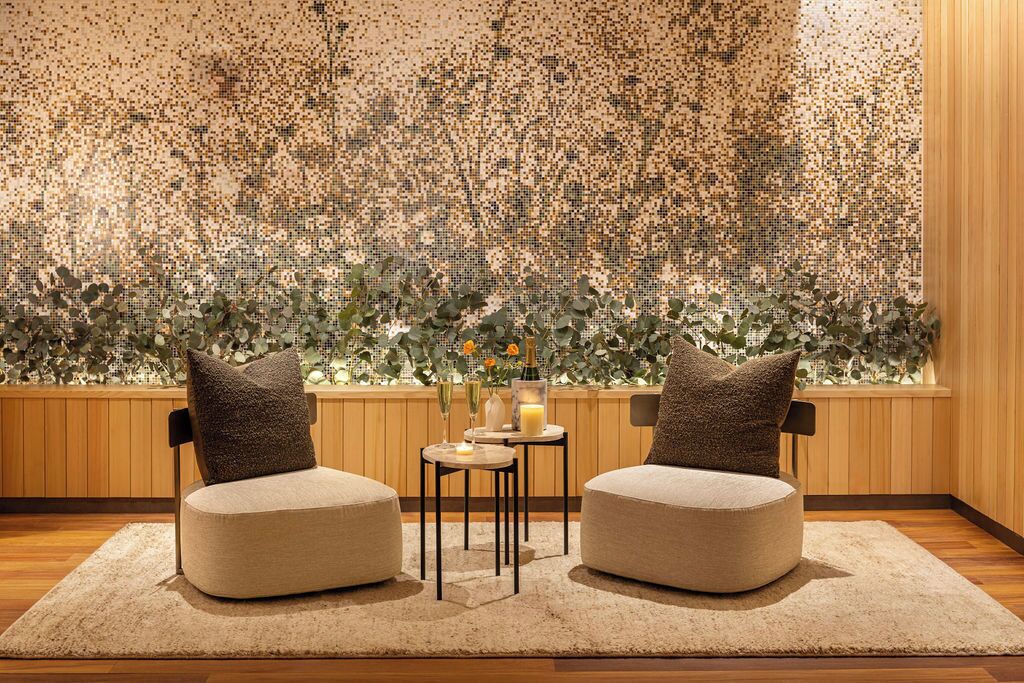 A room with two round seating areas, a small table with candles, and a mosaic wall.
