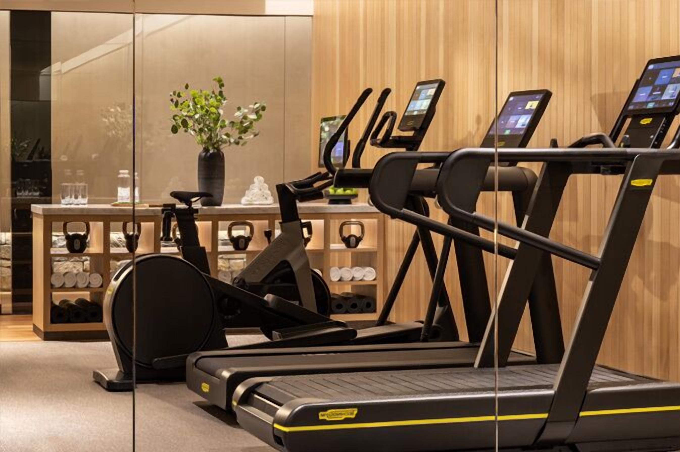 Ett modernt gym med löpband, en motionscykel och en viktbänk.